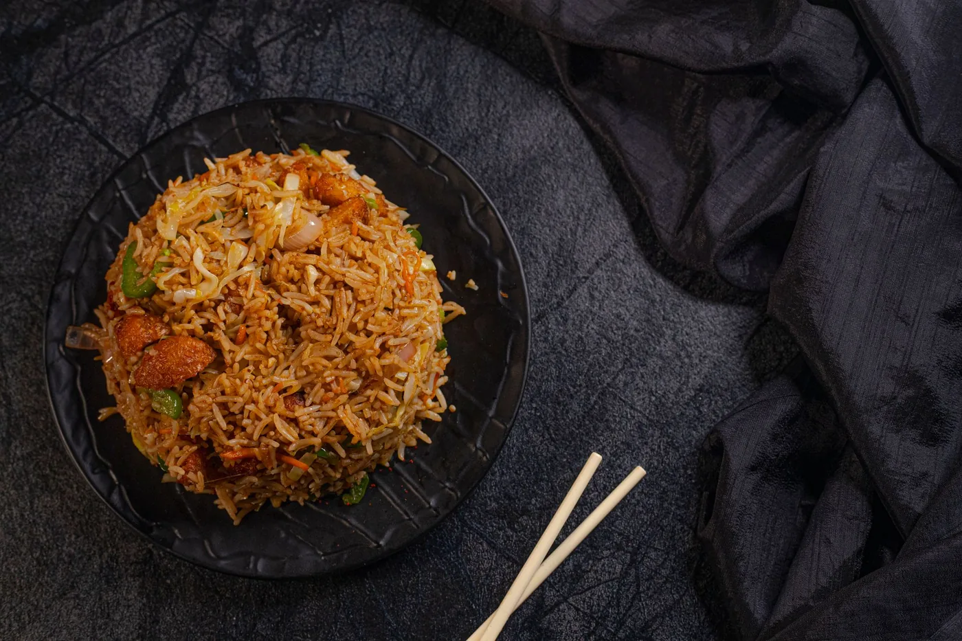 A plate of fried rice served with chopsticks