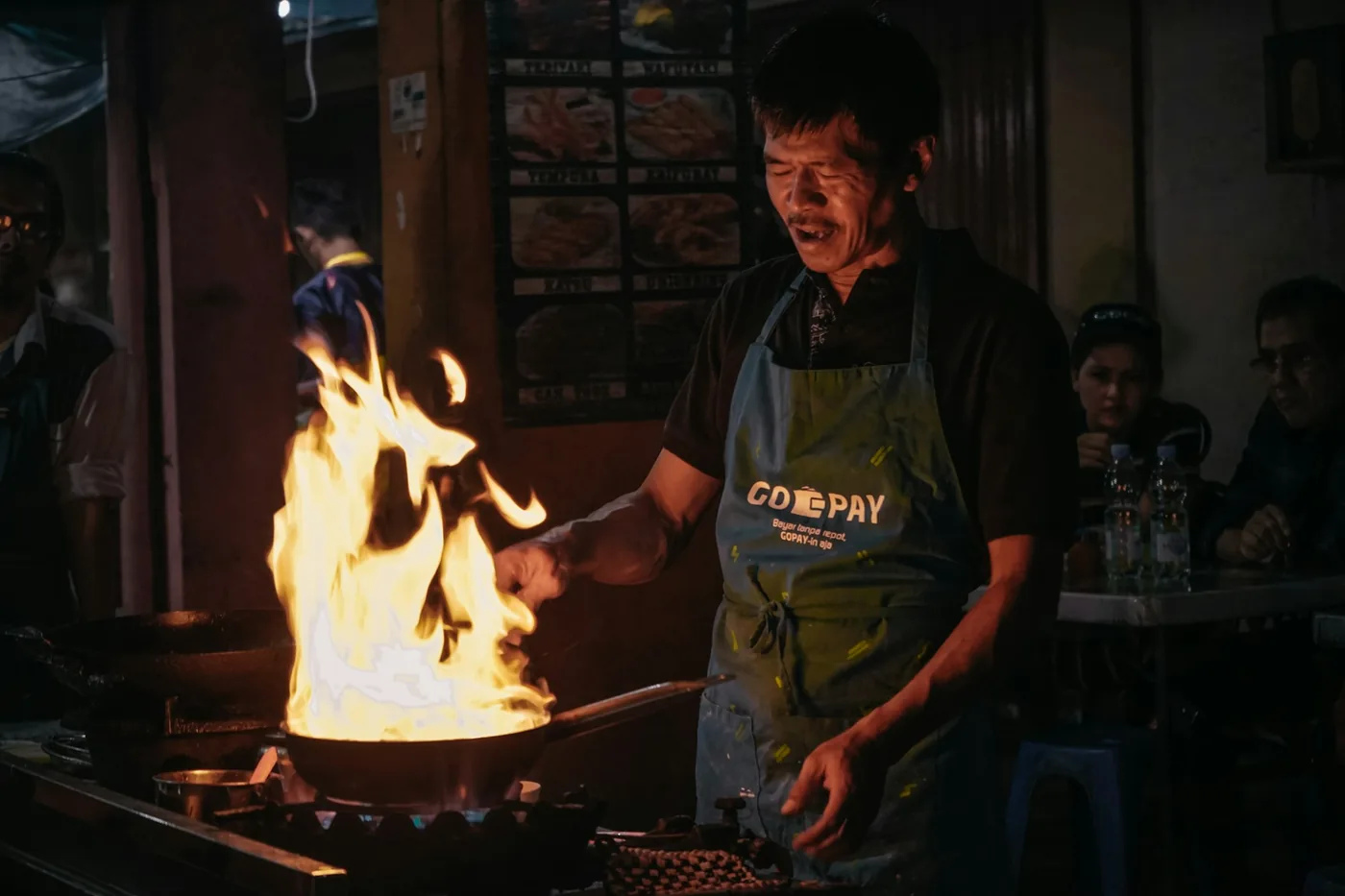 A cook working a wok over a high flame