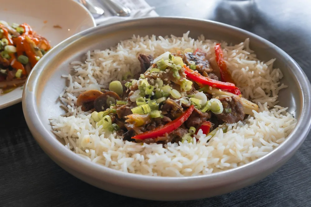 A stir fried dish served with rice in one bowl