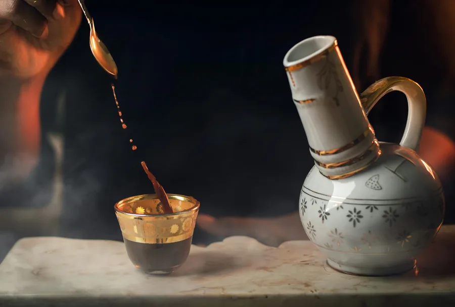 A dark sauce being poured into a small bowl