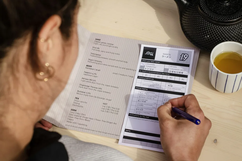 Someone reading a menu and writing an order