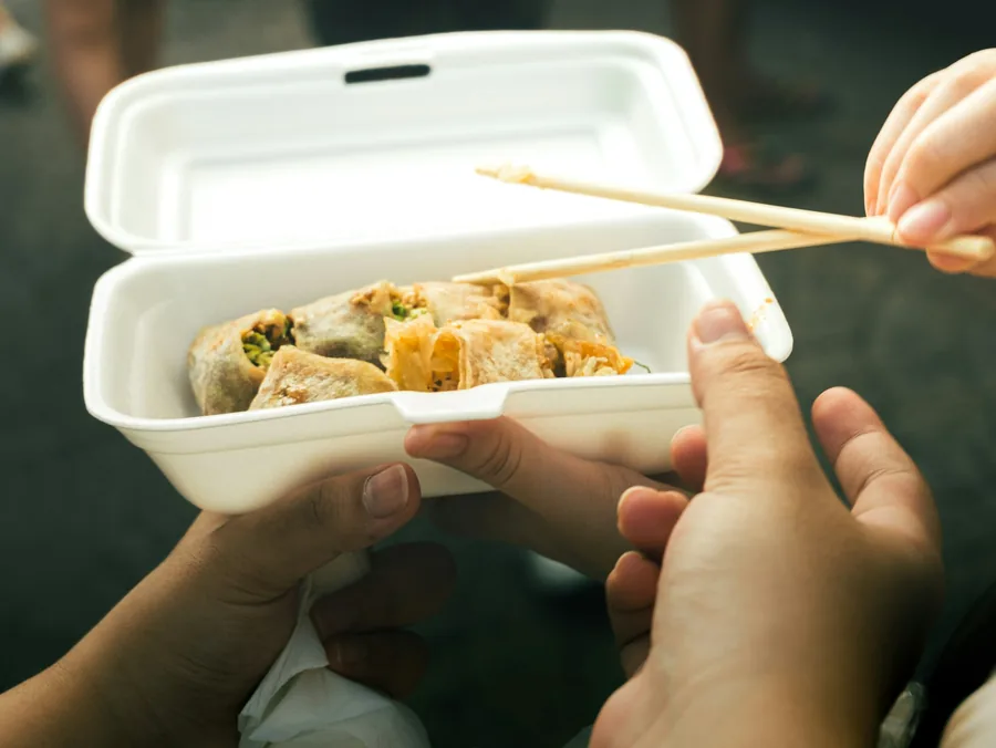 Eating from an open takeaway container with chopsticks