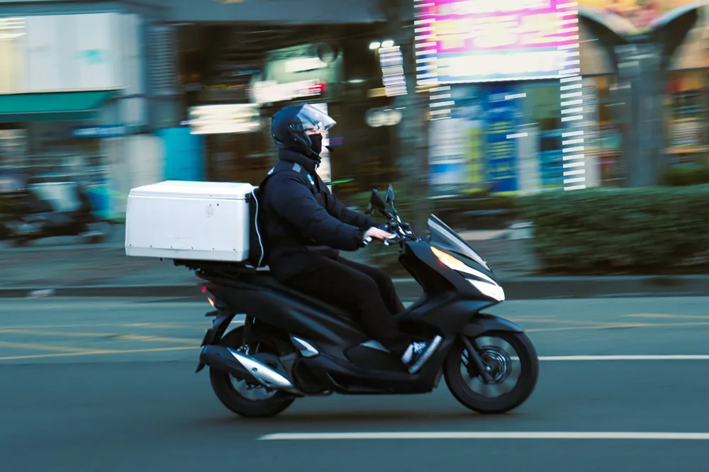 A delivery courier riding with an insulated box