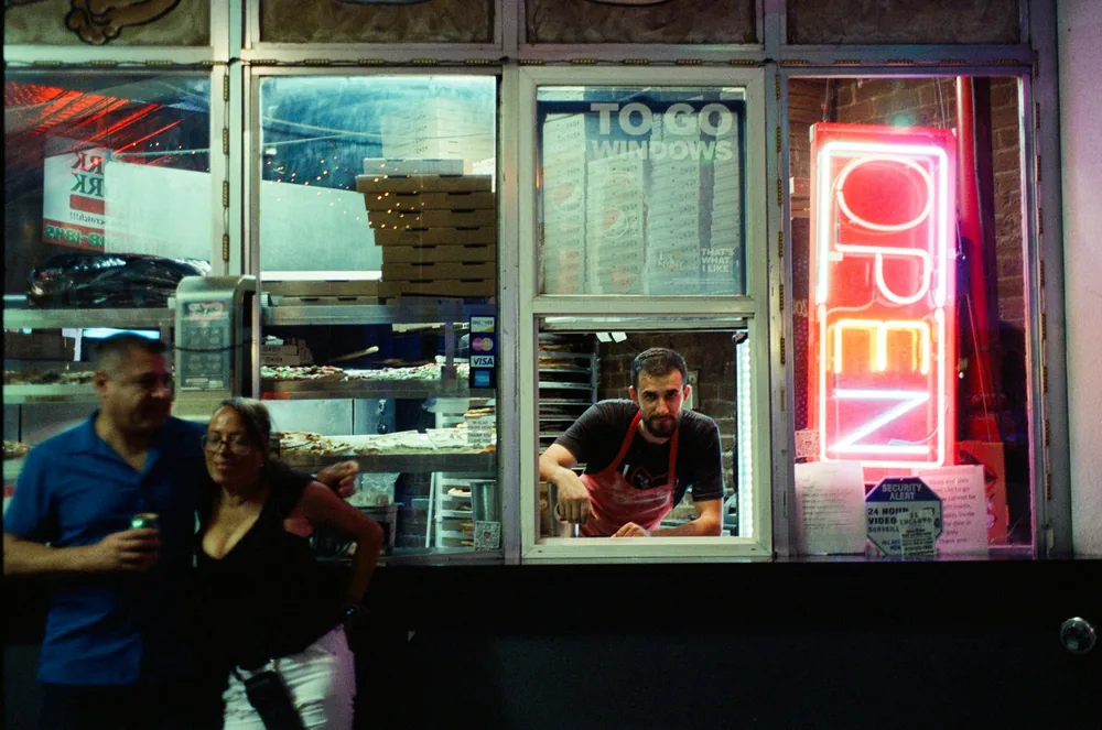 A lit takeaway window with customers waiting