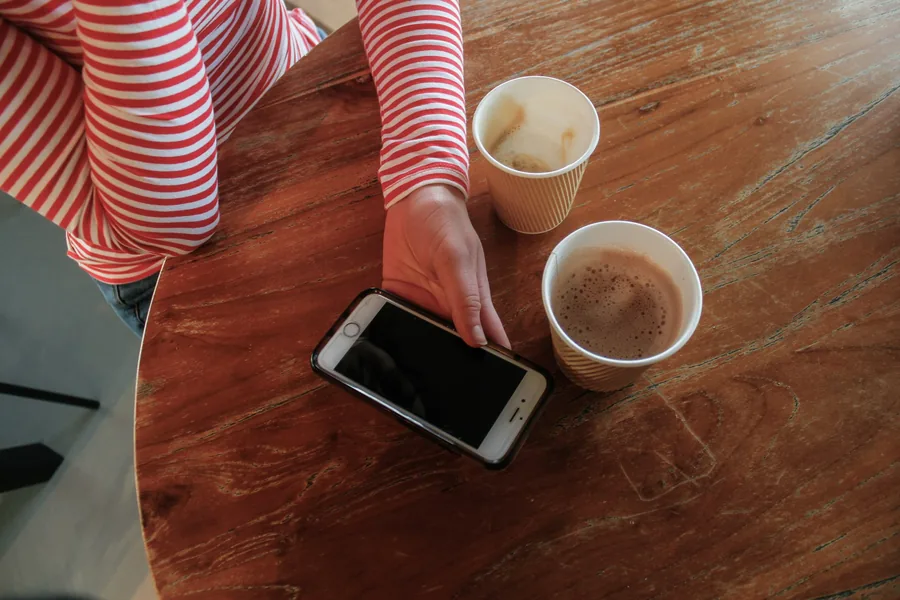 Checking a phone beside drinks on a table