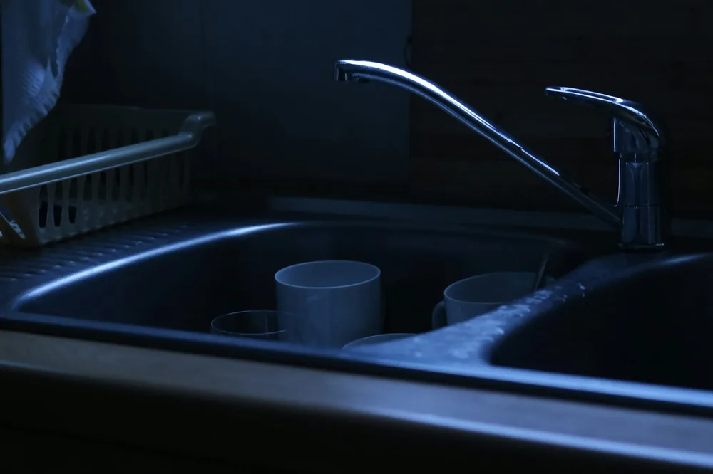 A kitchen sink with containers being rinsed