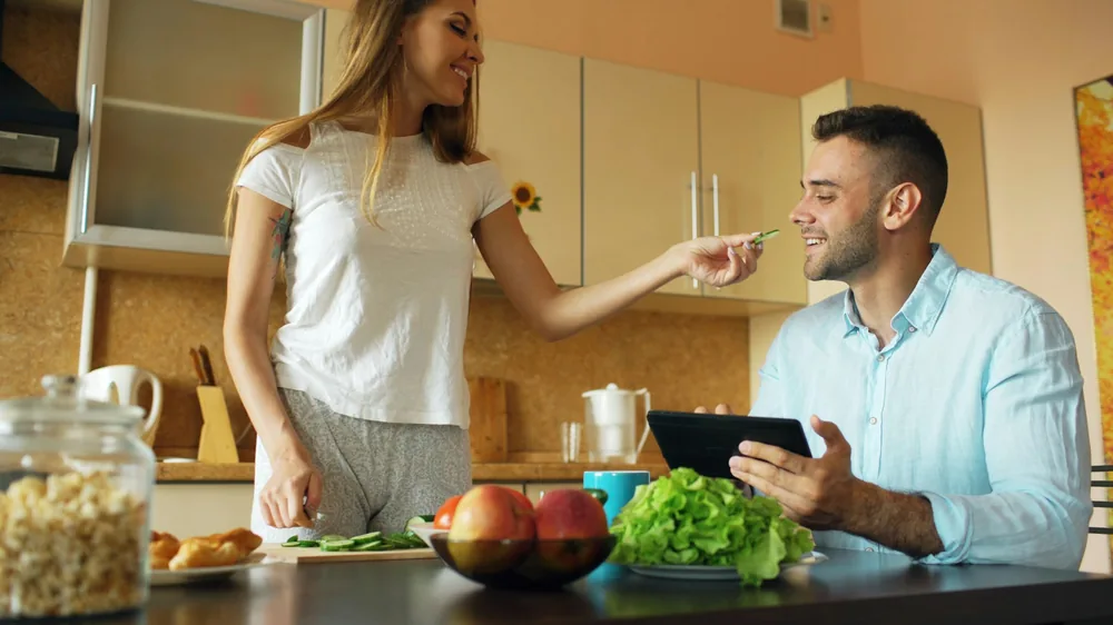 Two people sharing food in a kitchen
