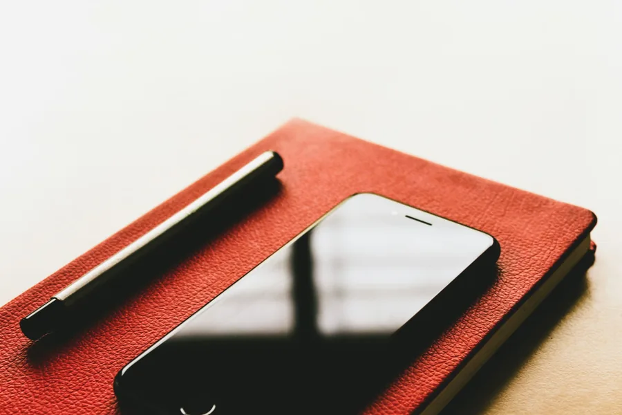 A notebook, pen and phone on a desk