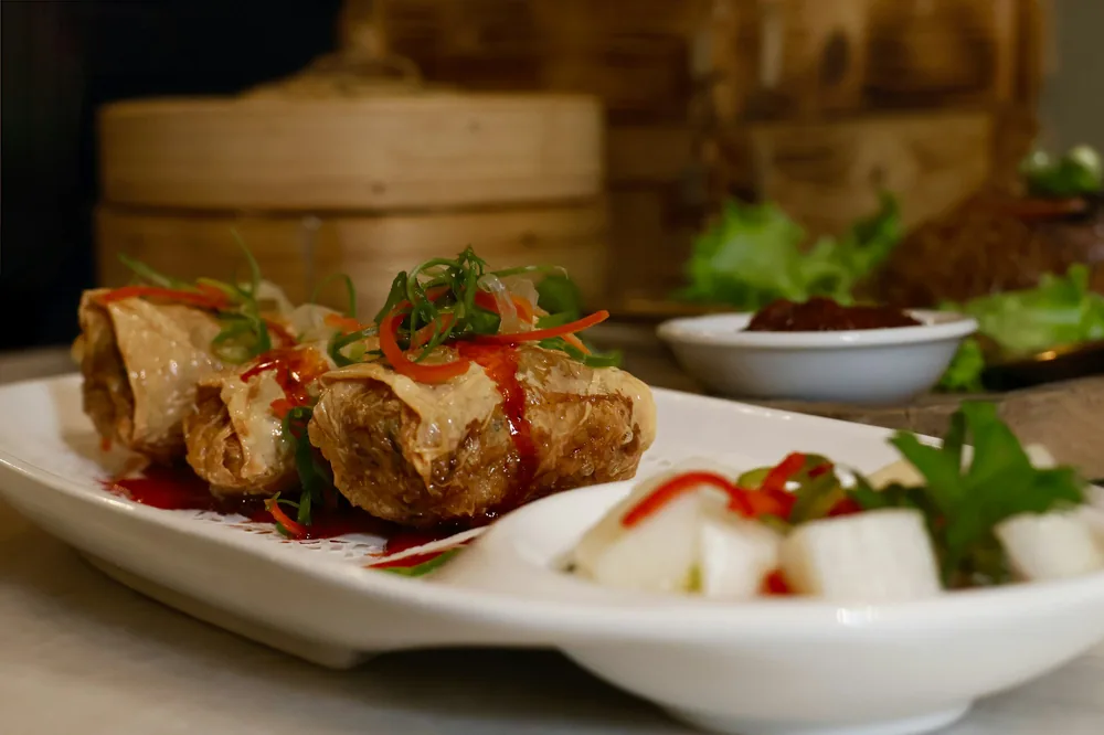 Egg rolls served on a plate with dipping sauce