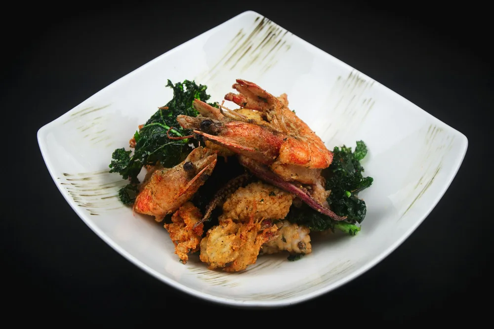 Shrimp served with greens on a plate