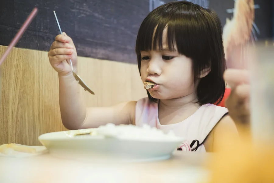 A child learning to eat with chopsticks