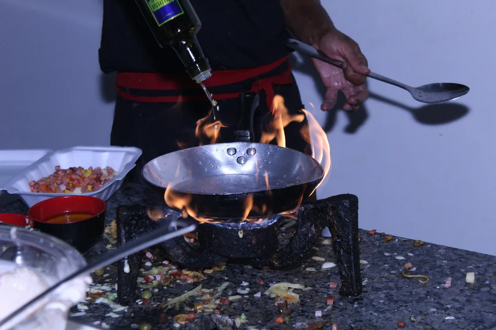 Rice being tossed in a wok over a flame