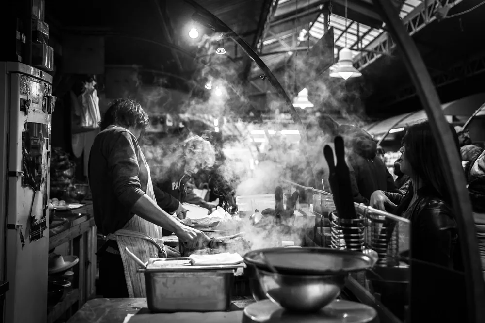 A busy restaurant kitchen with several woks in use