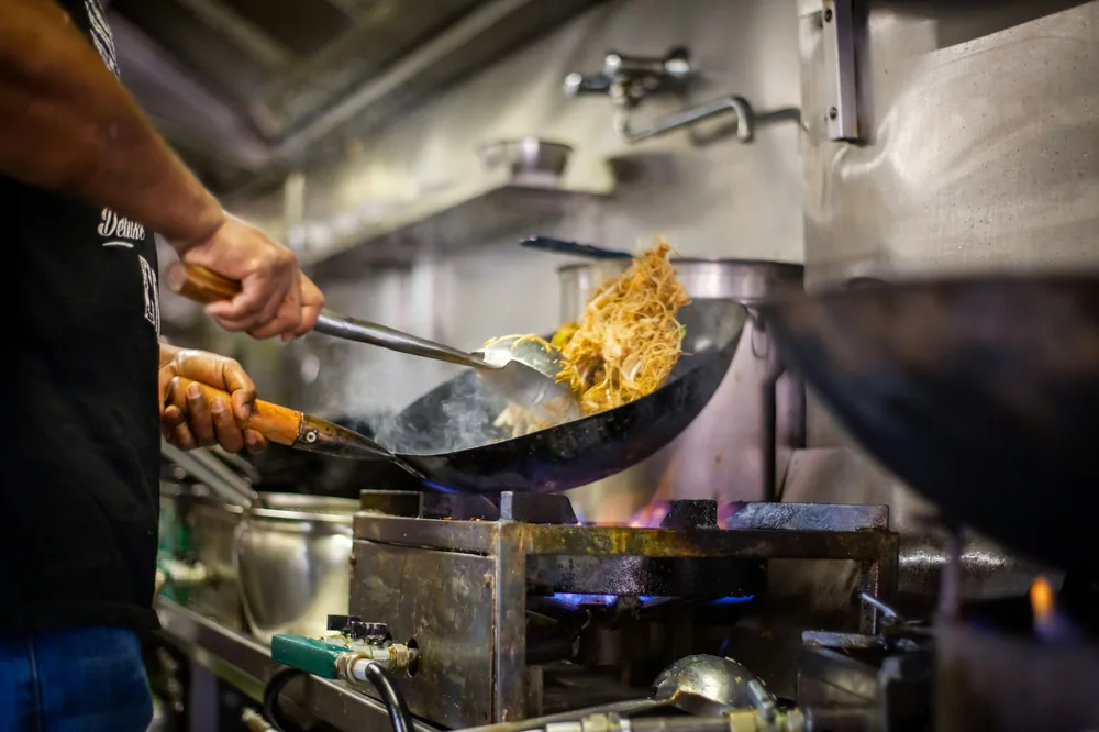 A cook tossing food in a wok