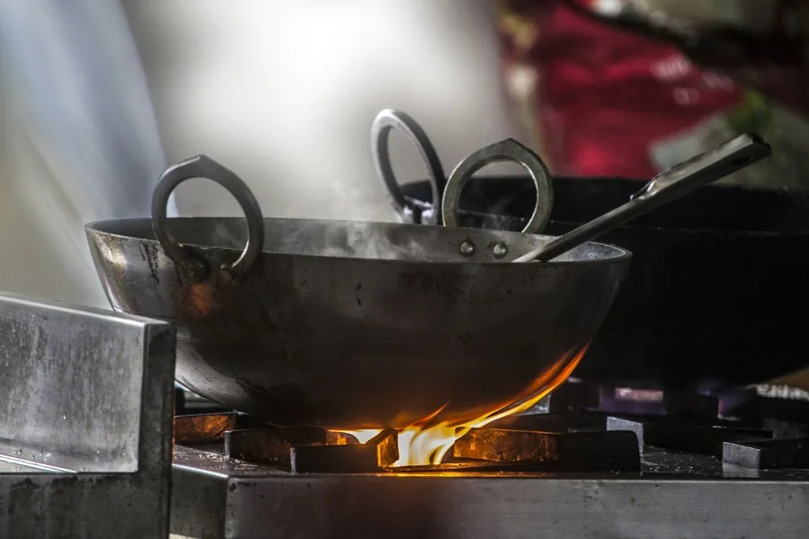 A carbon steel wok over a flame