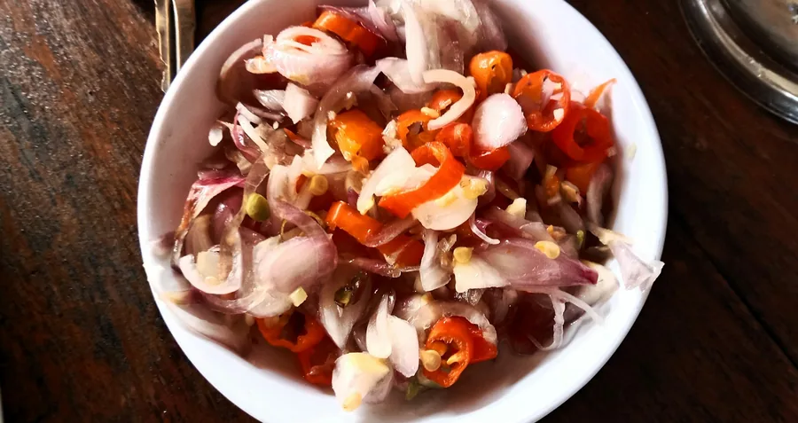 Raw chicken pieces marinating in a bowl