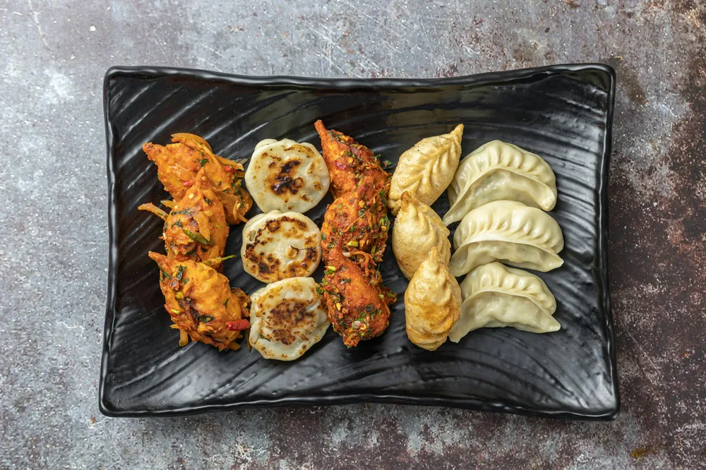A platter of Chinese appetizers including egg rolls and dumplings