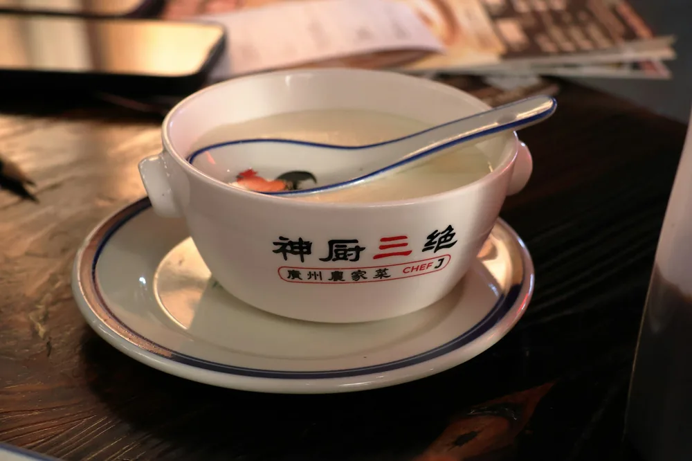 A bowl of golden egg drop soup with a spoon