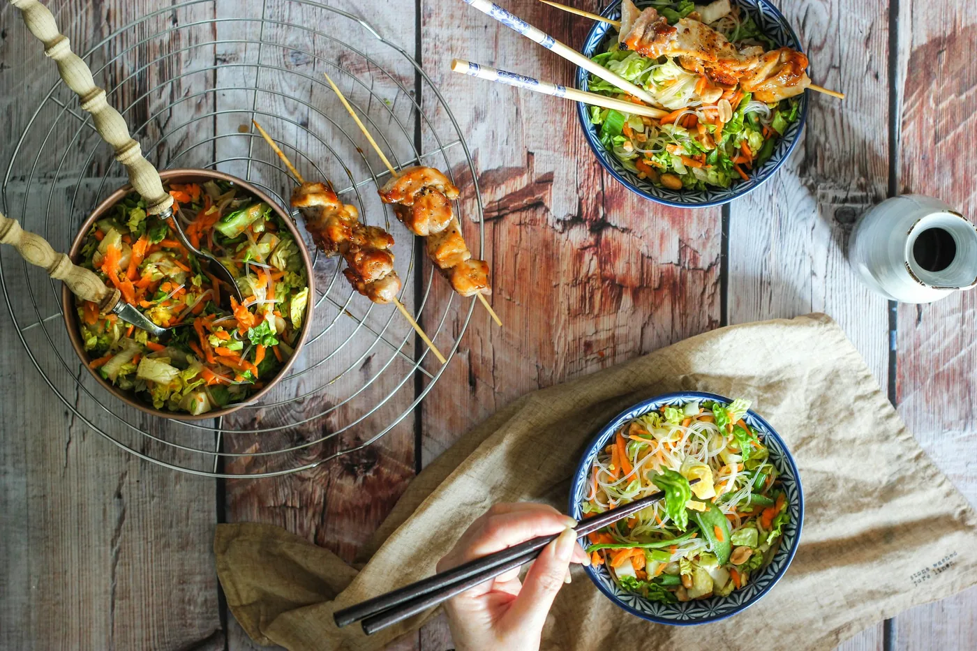 A bowl of rice beside a bowl of noodles, seen from above