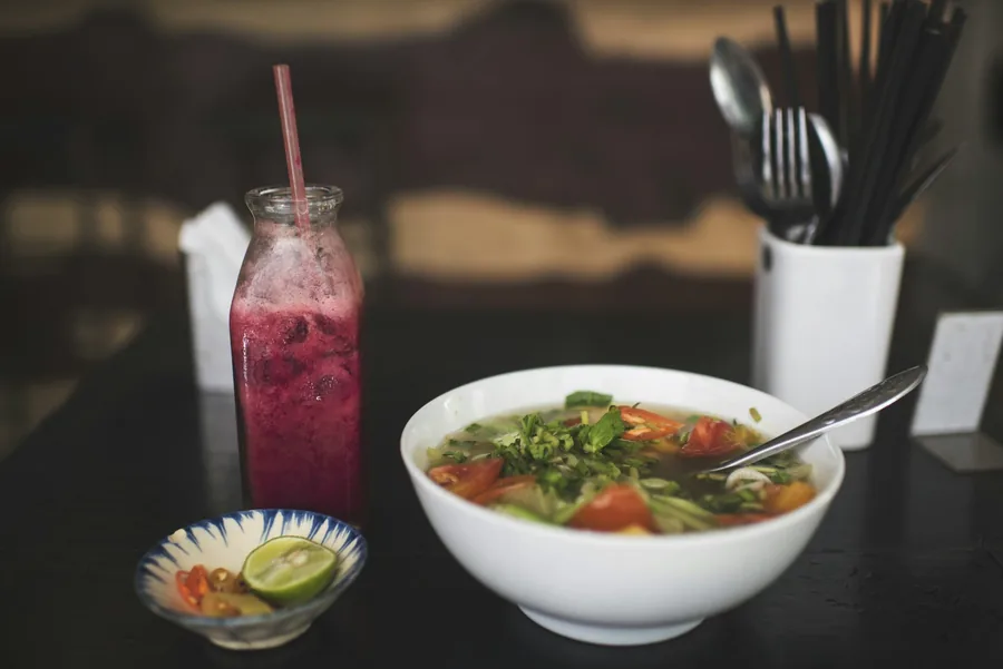 A cup of soup served alongside a drink