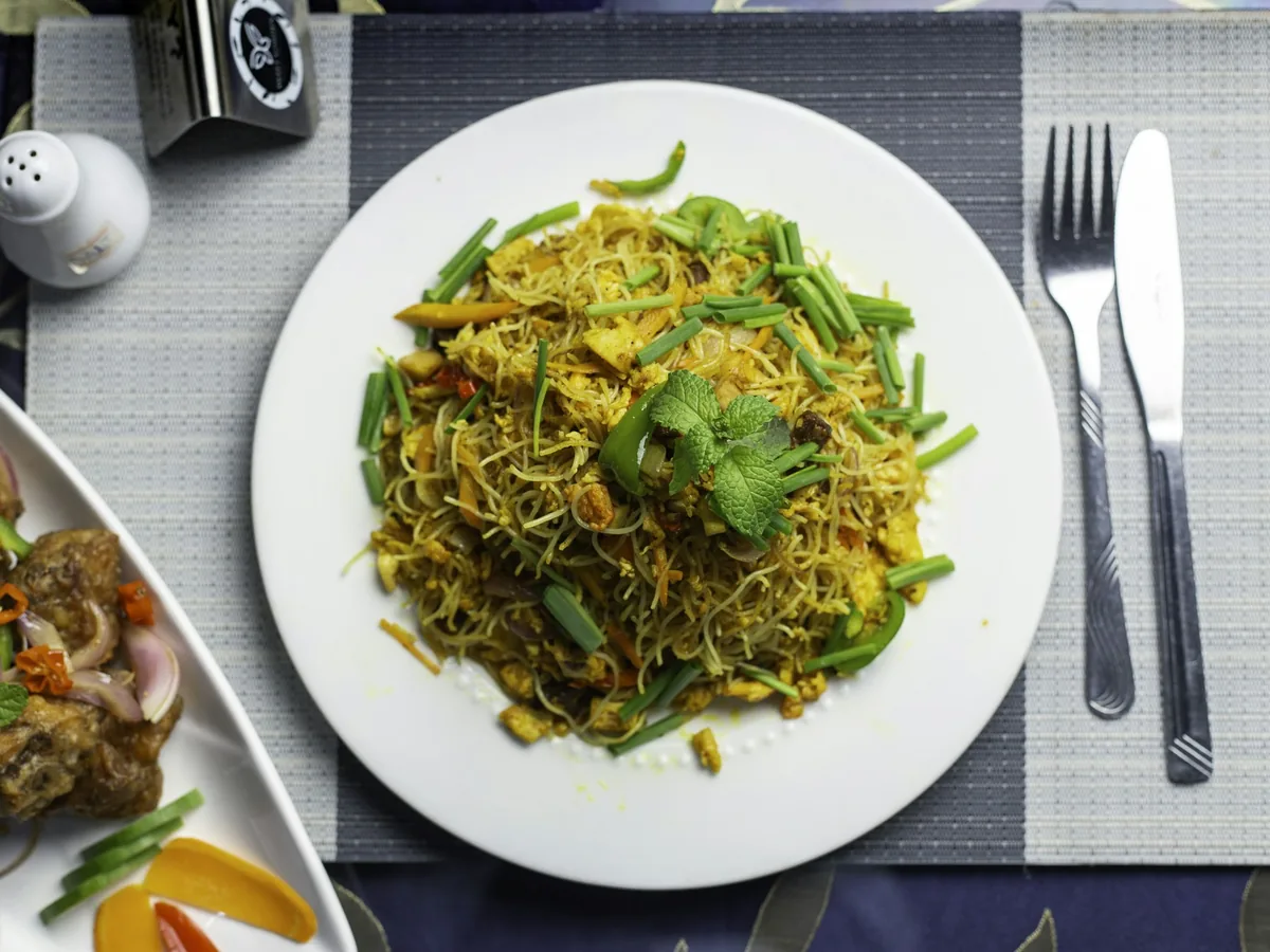 Thin curried rice noodles plated with fresh herbs
