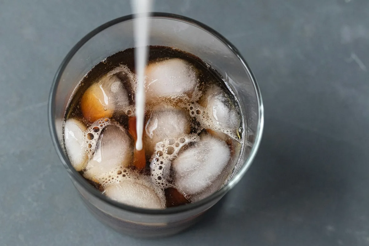 A soft drink being poured over ice