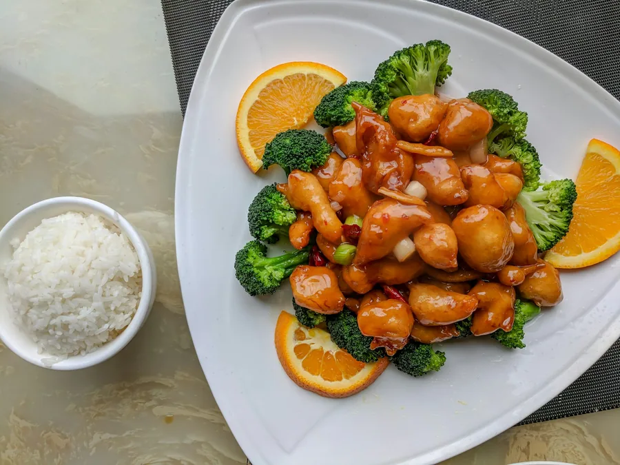 Orange chicken plated with broccoli and orange slices